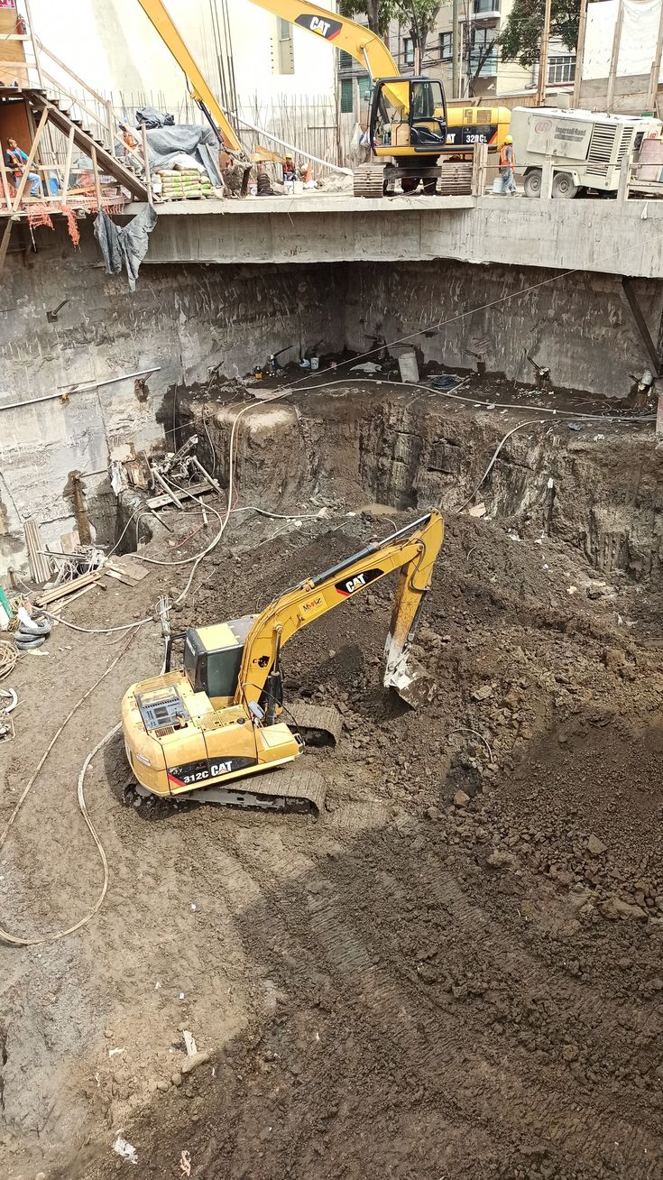 Escavadeira amarela trabalhando dentro de uma grande cava de obra